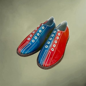 May include: A pair of bowling shoes featuring a color-blocked design with vibrant red and blue panels. The shoes have white eyelets for laces, white stitching details along the toe and sides, and a dark brown sole. The heel area is white.