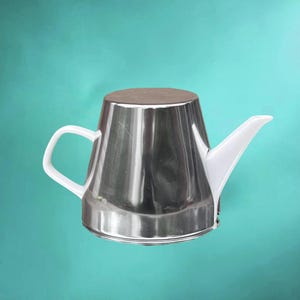 Op de afbeelding: Een theepot met een gepolijst zilverkleurig metalen lichaam, voorzien van een wit handvat en een witte tuit. Het vat heeft een brede, platte basis die naar boven toe taps toeloopt naar een platte bovenkant, in een afgeknotte kegelvorm.