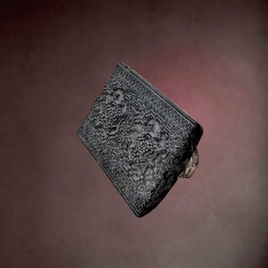 Könnte beinhalten: Ein rechteckiger schwarzer Ring mit einem komplexen, tief eingravierten Oberflächenmuster aus geometrischen Linien und Texturen. Die dunkle, matte Oberfläche bedeckt die gesamte Vorderseite des Rings, der auf einer seitlich sichtbaren Metallschiene sitzt.