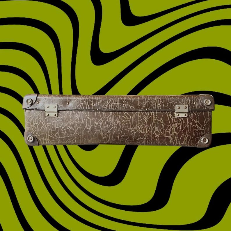 May include: A vintage brown suitcase with a textured surface and metal hardware. The suitcase is rectangular and has metal clasps and corner protectors. The background features a green and black wavy pattern.