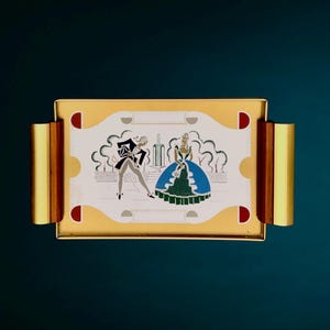 Peut inclure: Un plateau de service rectangulaire avec une surface en métal doré et des poignées latérales en bois. Le centre présente un panneau blanc avec une illustration graphique de deux personnages en costume d'époque près d'une fontaine, avec des motifs rouges.