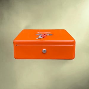 May include: A bright orange metal cash box with a rectangular shape and rounded corners. The top features a silver handle and a silver key attached to a red plastic coil wristband. A circular silver keyhole is centered on the front panel.
