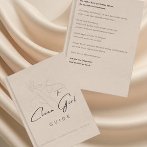 Könnte beinhalten: Zwei geöffnete Bücher mit dem Titel "The Clean Girl Guide" auf cremefarbenem Hintergrund. Das Cover zeigt eine minimalistische Strichzeichnung einer Frau und den Titel in eleganter Schrift. Das offene Buch zeigt Text.