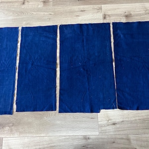 Puede incluir: Cuatro piezas rectangulares de tela azul oscuro están dispuestas en fila. Cada pieza de tela presenta un color azul profundo sólido con una textura tejida visible y bordes rectos sin rematar, mostrando una apariencia consistente en todos.