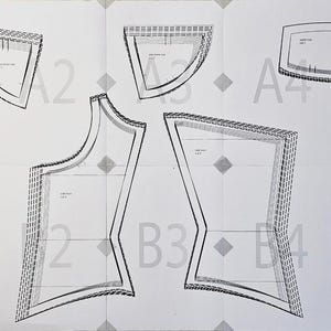 K&ouml;nnte beinhalten: Ein wei&szlig;er Schnittmusterbogen mit schwarz umrandeten Kleidungsst&uuml;cken, die mit A1 bis A5 und B1 bis B5 beschriftet sind. Das Schnittmuster enth&auml;lt verschiedene geometrische Formen mit gestrichelten Nahtzugabelinien und Markierungen.