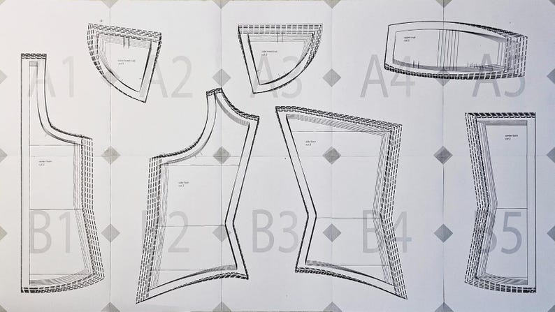K&ouml;nnte beinhalten: Ein wei&szlig;er Schnittmusterbogen mit schwarz umrandeten Kleidungsst&uuml;cken, die mit A1 bis A5 und B1 bis B5 beschriftet sind. Das Schnittmuster enth&auml;lt verschiedene geometrische Formen mit gestrichelten Nahtzugabelinien und Markierungen.