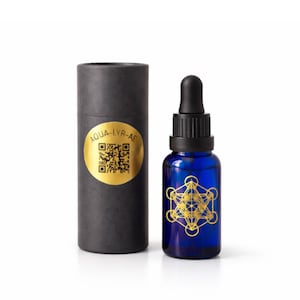 May include: A blue glass dropper bottle with a black cap and a gold geometric design, next to a black cylindrical container with a gold label that reads "AQUA-LYR-AE". The bottle contains a liquid.