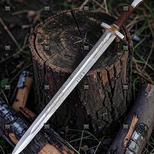 Può includere: Una spada d'argento con manico e guardia in legno è appoggiata su un ceppo. La lama presenta disegni di nodi celtici incisi e rune. L'impugnatura è avvolta in pelle marrone. La spada è circondata da legno ed erba.