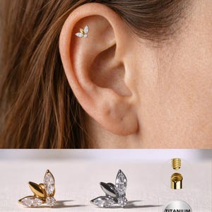 Puede incluir: Una taza de cerámica blanca con un asa negra y el texto "But First, Coffee" en un estilo manuscrito. La taza está sobre una superficie blanca. La taza mide aproximadamente 10 cm de alto.