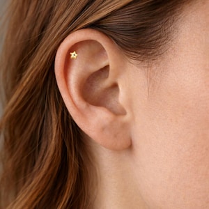 Puede incluir: Una taza de cerámica blanca con un asa negra y el texto "But First, Coffee" en negro y negrita. La taza está sobre una superficie de madera.