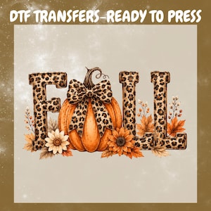 May include: A DTF transfer graphic featuring the word FALL in block letters with a brown and black leopard print pattern. An orange pumpkin with a matching leopard print bow sits in the centre, surrounded by autumn leaves and flowers.