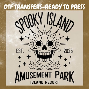 May include: A beige DTF transfer with a black graphic of a skull with sun rays, the text "SPOOKY ISLAND AMUSEMENT PARK ISLAND RESORT", and the year "2025". The text "DTF TRANSFERS - READY TO PRESS" is at the top.