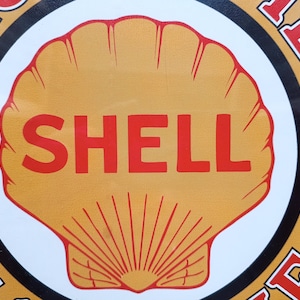 Könnte beinhalten: Vintage Shell Oil Company Werbeschild mit einem großen, orangefarbenen Muschellogo und dem Wort "SHELL" in Rot. Das Logo befindet sich auf einem gelben Hintergrund mit einem weißen und schwarzen Rand. Der Text "MOTOR OIL" ist rot.