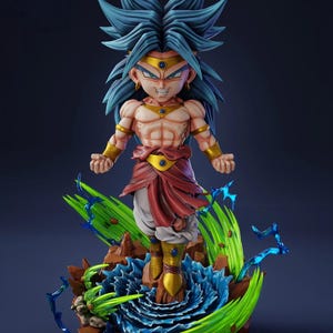 Puede incluir: Figura detallada de un personaje con pelo azul puntiagudo, detalles dorados y una expresión decidida. La figura se alza sobre una base con efectos de energía verdes y azules, mostrando una pose dinámica. El personaje viste un atuendo rojo y blanco.