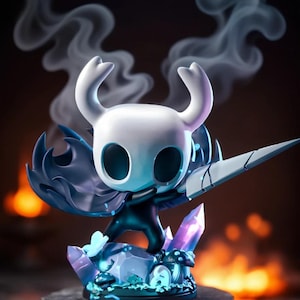 Op de afbeelding: Een beeldje van een personage uit de videogame Hollow Knight. Het beeldje heeft een witte kop met hoorns, een donkerblauwe cape en een groot zwaard. Het staat op een voetstuk met blauwe kristallen en paddenstoelen, met rook op de achtergrond.