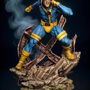 Può includere: Una statuetta dettagliata di Ciclope, un supereroe, in una posa dinamica. Indossa un costume blu e giallo con un'emblema rosso. La figura è in piedi su una base rocciosa con una struttura metallica a forma di X, con effetti di fumo sullo sfondo.