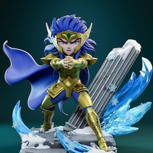 Puede incluir: Figura detallada de un personaje con armadura dorada con detalles azules, una capa azul y cabello azul. La figura está posada sobre una base de piedra con detalles de hielo y nieve, y una columna rota. El personaje tiene una expresión intensa.