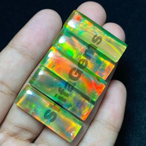 May include: Four rectangular, polished opal gemstones arranged in a vertical row. Each stone displays a vibrant play-of-colour with flashes of neon green, orange, and yellow. The text shifagems is printed diagonally across the surface of the stones.