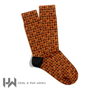 May include: A pair of Halloween-themed socks with a repeating pattern of jack-o'-lantern faces on a black and orange plaid background. The socks have black heels and toes, and the text "COOL & FUN SOCKS" is visible.
