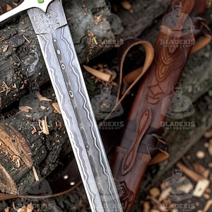 May include: A detailed image of a sword with a patterned blade and a wooden handle. The sword is silver and brown, with a leather sheath. The blade has a unique wave-like pattern. The sheath is brown with carved designs.