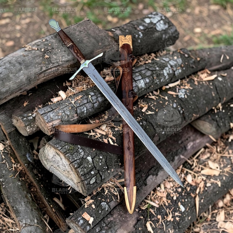 May include: A long, ornate sword with a patterned blade and a wooden handle, resting on a pile of logs. The sword has a silver crossguard and a matching pommel. A leather sheath with gold accents and a brown leather belt are also present.