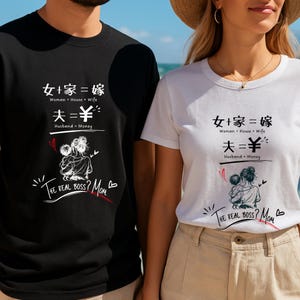 以下が含まれることがあります： グラフィックデザインの黒と白のTシャツ。デザインには、中国語の文字と英語の翻訳、母親と子供のイラストが含まれています。テキストは「The Real Boss？Mom」と書かれています。