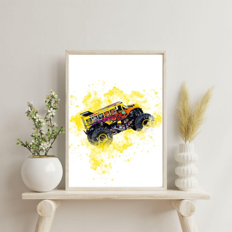 May include: Framed print of a monster truck in yellow and orange, with black wheels and a colourful graphic. The background features a yellow watercolour effect. The artwork is displayed in a wooden frame, adding a decorative touch.