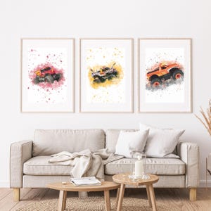 May include: Three framed prints showcasing watercolour monster trucks in red, white, and orange. Each truck is set against a colourful splash background. The prints are displayed above a beige sofa, adding a vibrant touch to the room.