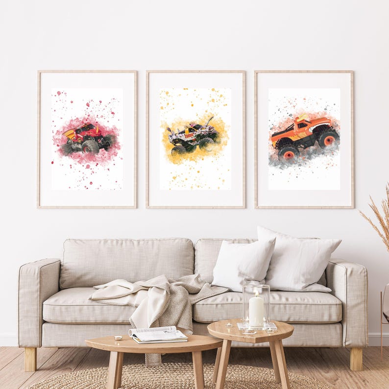 May include: Three framed prints showcasing watercolour monster trucks in red, white, and orange. Each truck is set against a colourful splash background. The prints are displayed above a beige sofa, adding a vibrant touch to the room.