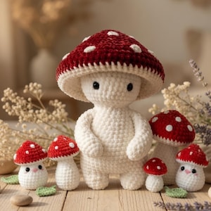May include: A collection of handmade crochet mushroom figures. The large central figure has a red and white spotted cap and a white body. Smaller mushrooms with red caps and white spots are arranged around it. The figures are on a wooden surface.