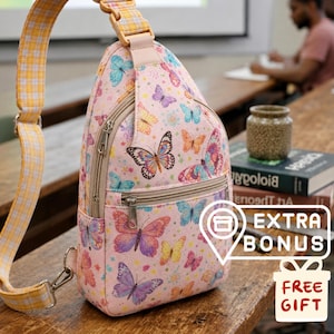 May include: Pink sling bag with a butterfly pattern. The bag has a zippered main compartment and a yellow plaid strap. The bag is decorated with colorful butterflies in various sizes and colors.