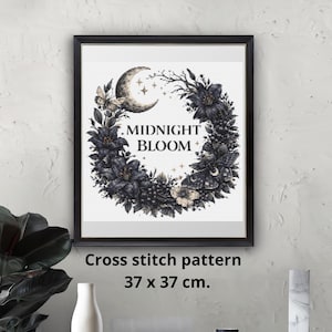 May include: Framed art print featuring a floral wreath design with a crescent moon and stars, with the words "MIDNIGHT BLOOM". The cross stitch pattern measures 37 x 37 cm.