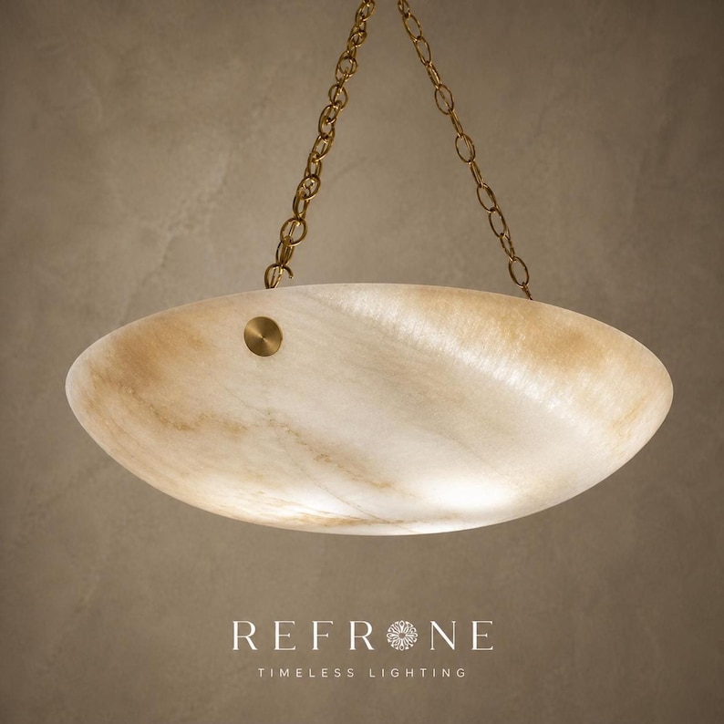 Angled underside view of creamy translucent alabaster pendant light, soft stone veining, brass chain visible