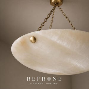 Close side detail of alabaster bowl pendant rim, natural stone veins and a brass rivet accent on the shade