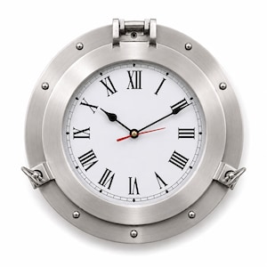 May include: A circular wall clock designed like a nautical porthole with a brushed silver metal frame. The white clock face features black Roman numerals, two black hour and minute hands, and a thin red second hand. The frame includes rivets.