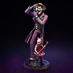 May include: A detailed statue of the Joker in a purple suit and hat, holding a camera, with a smaller figure in a pink dress and bow. The base is a circular platform with a fence design.