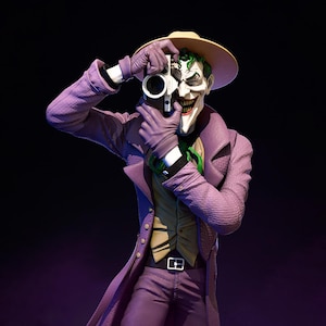 May include: A figurine of the Joker in a purple suit, holding a camera. The Joker is wearing a tan hat, purple gloves, and a green tie. The figure has a sinister grin and green hair. The background is dark.