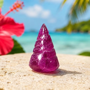May include: A cone-shaped sculpture carved from translucent deep magenta stone with a faceted, crystalline texture. The object features a pointed top and a wide, rounded base, displaying internal fractures and light-reflecting surfaces throughout.