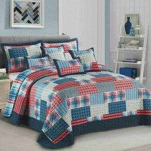 May include: A bed dressed with a patchwork quilt and matching pillows. The quilt displays a pattern of red, blue, and grey squares. The pillows echo the design. The bed is made up and ready for use.