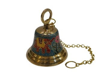 May include: A brass bell with a decorative design featuring an elephant and floral patterns in red, yellow, and pink against a teal background. The bell has a chain and a loop for hanging.