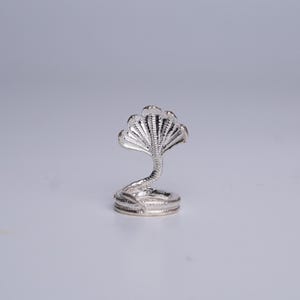 Könnte beinhalten: Eine silberne Kobra-Figur mit ausgestellter Kapuze und gewundenem Körper. Die Schlange ist mit geätzten Mustern versehen und steht auf einem kreisförmigen Sockel. Die Figur besteht aus glänzendem, reflektierendem Metall.