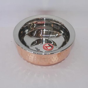 Puede incluir: Un juego de tres tazas de cerámica con un esmalte moteado de color crema. Cada taza presenta un diseño pintado a mano diferente: una hoja azul y verde, una flor amarilla y una baya roja. Las tazas tienen una forma simple y redondeada.