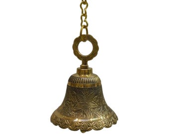 May include: A brass bell with a floral design, suspended by a gold-colored chain. The bell has a flared base and a decorative top with a circular design. The bell is likely used for decorative purposes.