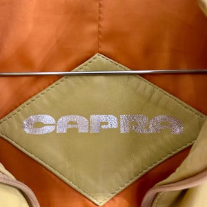 May include: A white ceramic mug with a black handle and the text "But First, Coffee" in a black, bold font. The mug is sitting on a white surface.