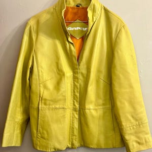 May include: A white ceramic mug with a black handle and the text "But First, Coffee" in a black, handwritten-style font. The mug is on a white surface.