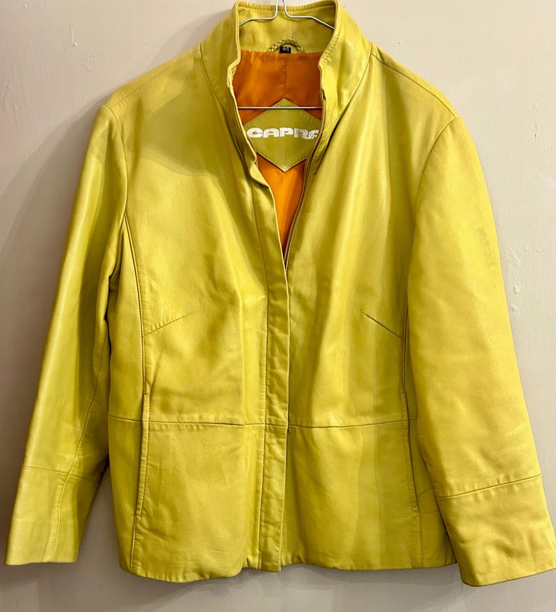 May include: A white ceramic mug with a black handle and the text "But First, Coffee" in a black, handwritten-style font. The mug is on a white surface.