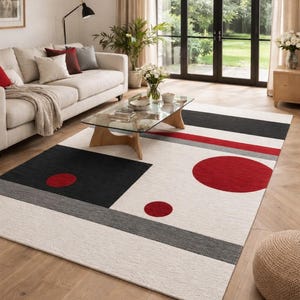 Può includere: Un tappeto rettangolare con un motivo geometrico su sfondo color crema, caratterizzato da un grande quadrato nero, una lunga striscia orizzontale nera, una striscia grigio scuro e tre cerchi rossi pieni di dimensioni variabili sulla superficie.