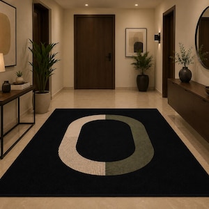 Può includere: Un tappeto rettangolare nero con un design astratto bianco, beige e verde oliva. Il tappeto è in un corridoio con porte in legno, una console e uno specchio rotondo. La palette di colori è neutra.