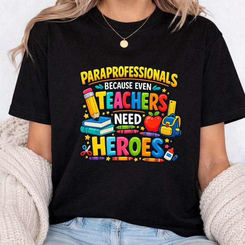 May include: Black t-shirt with a colorful graphic that reads "PARAPROFESSIONALS BECAUSE EVEN TEACHERS NEED HEROES." The design includes a pencil, books, apple, backpack, and other school supplies.