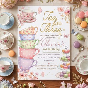 Puede incluir: Una tarjeta de invitación de cumpleaños con una pila de cinco tazas de té coloridas con motivos florales y de lunares, una bandeja de macarons y mariposas. El texto dice Tea for Three, join us for a tea party to celebrate Olivia's 3rd Birthday.